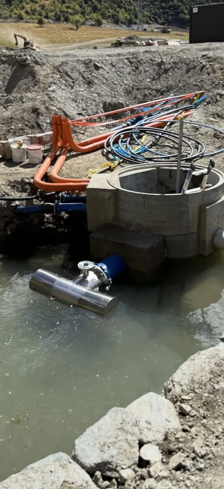 Stainless intake screen and concrete chamber in a pond, with pipes and cables laid alongside
